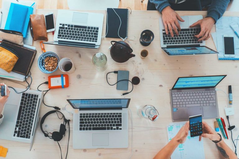bird's eye view of workers at table on laptops and phone