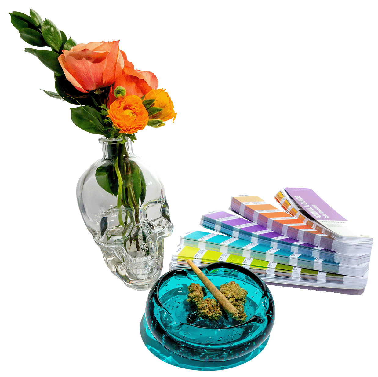 pantone swatches nest to clear skull vase holding flowers by a blue glass ashtray holding cannabis flower and joint