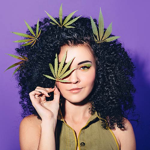 young woman with cannabis leaves in her hair